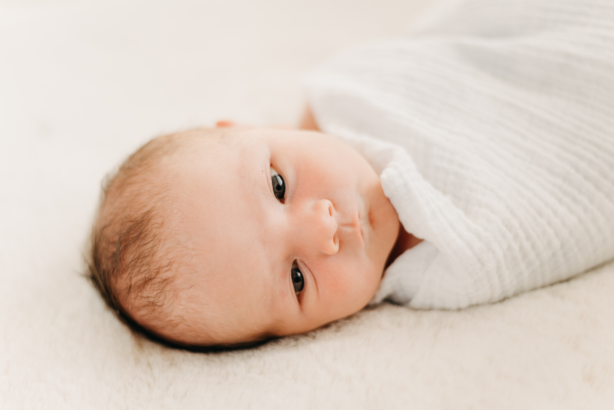 baby lying down wrapped in white swaddle