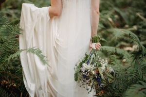 photo by kelowna wedding photographer of bride holding bouquet and her dress on her wedding day