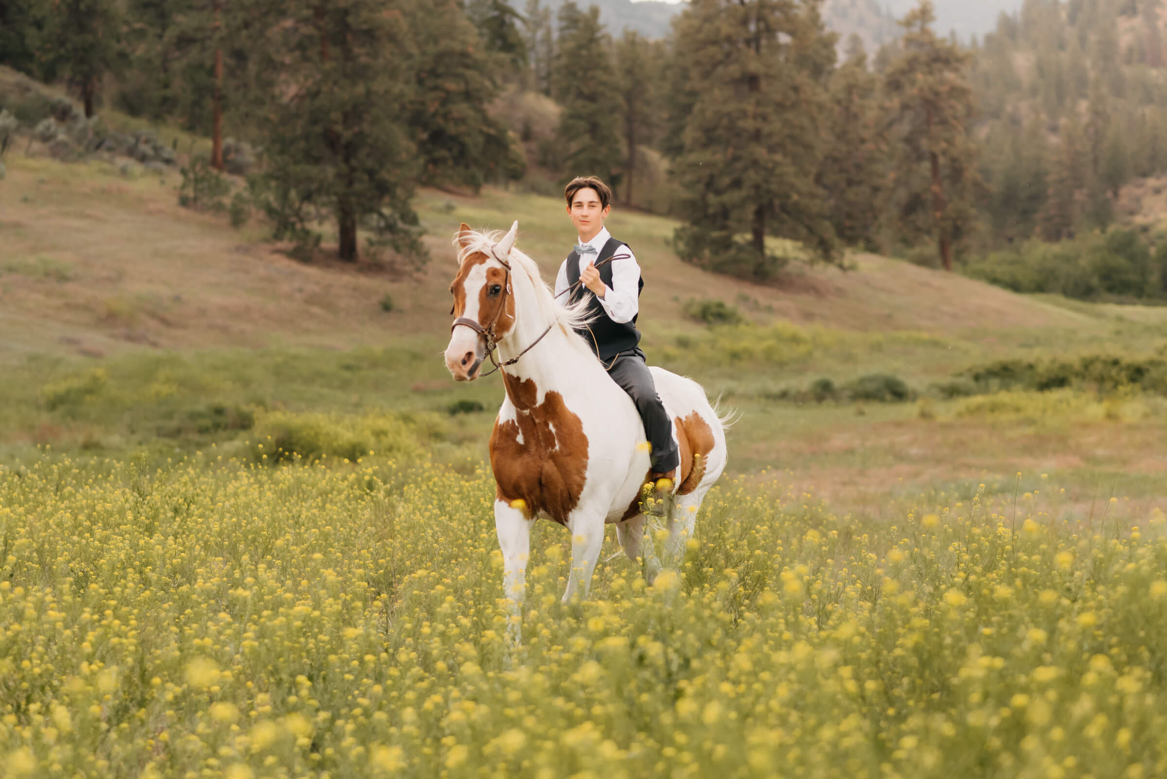 teenage boy riding horse through a field. horse benefits from Kelowna equine bodywork therapy