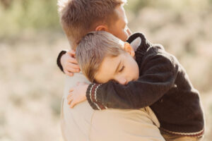 boy hugs his dad with his eyes closed at Penticton counselling session