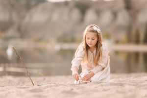 girl builds tower with sticks at the Penticton beach